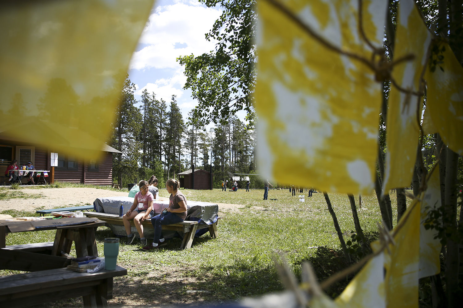 Two mountain camp attendees relax on one of the picnic benches